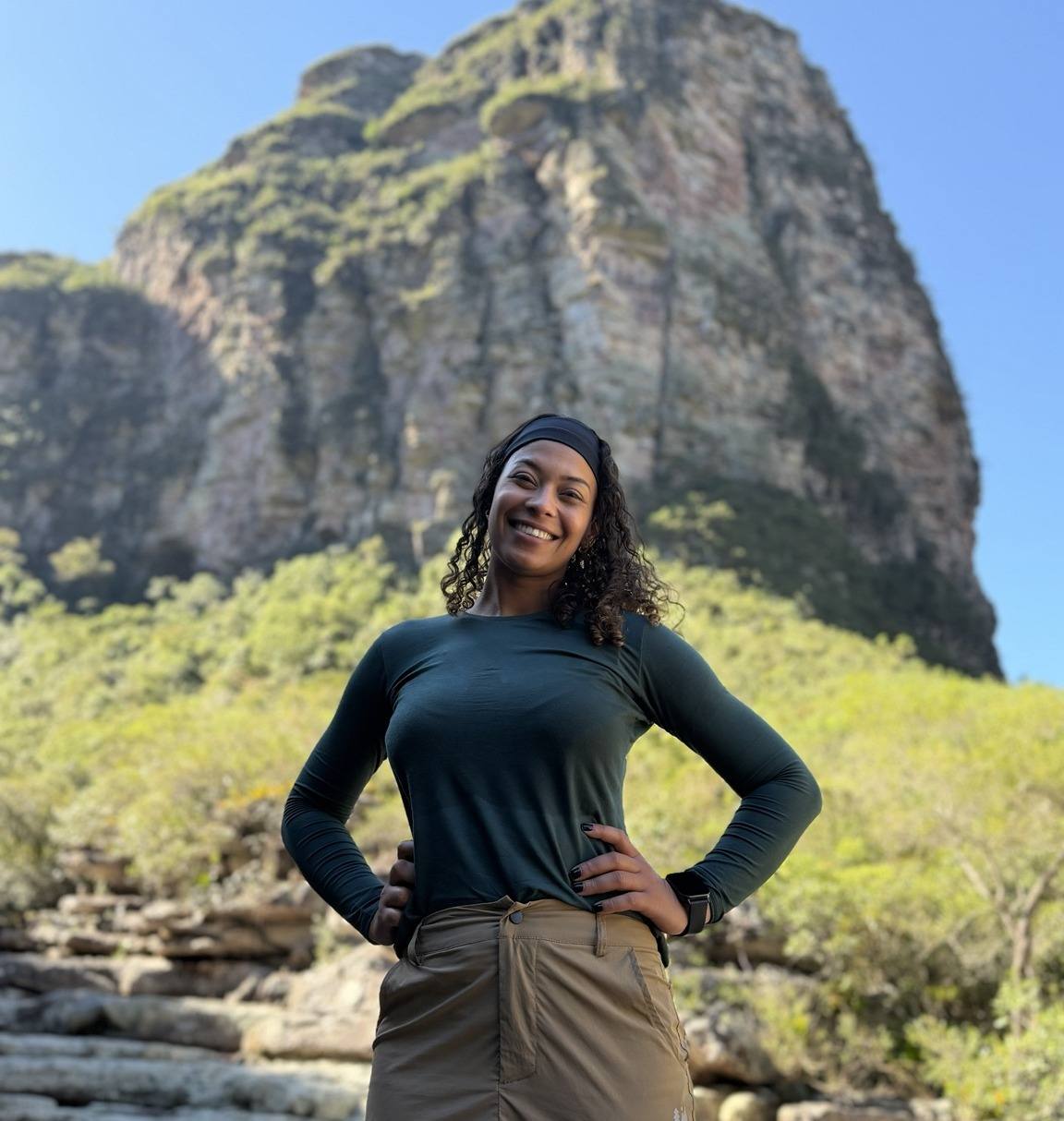 Michele sorrindo diante de um paredão de pedra na Chapada Diamantina